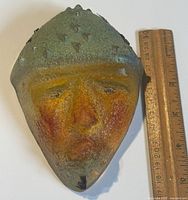 Front view of the primitive man sculpture next to a ruler showing approximately 6 inches in length.