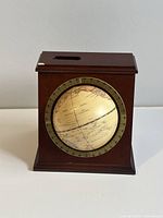 Front view of the vintage globe set inside a wooden stand, showing the globe in an antique map style with degree ring around it.