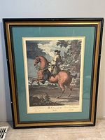 Photo of the framed vintage print depicting a rider on a brown horse titled "Le Galop a Gauche," showing overall condition and framing details.
