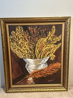 Front view of the vintage framed oil painting showing floral still life in a white vase with a dark background. The ornate gold tone wooden frame is visible.