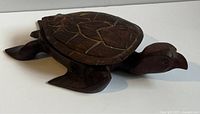 Side profile image of the carved wooden turtle box showing detailed shell carvings and dark wood finish.