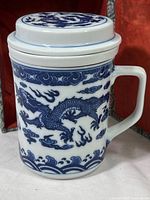 Blue and white Chinese ceramic tea mug with dragon design, side view showing handle and decoration.