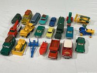 Twenty die cast vehicles arranged in four rows showing variety and condition, including cars, bicycles, and tractors with wear.