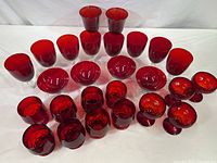 Full group layout of 26 ruby red glasses including tumblers, sherbets, stemmed champagne glasses, water/wine goblets, and larger goblets.