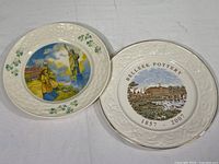 Two Belleek collectible plates displayed side by side showing front design and backside detail with gold rim on one plate visible