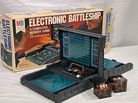Full setup of the Vintage MB Electronic Battleship game including game console, two cubes with red and white playing pieces, and original game box in background.