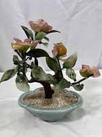 Front and side views of the artificial glass composite bonsai tree showing pink flowers, green leaves, yellow buds, and a blue ceramic pot with white gravel.