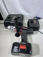 Image showing Craftsman cordless hammer drill with DieHard 19.2V battery attached, alongside a dual and single Craftsman battery charge units on a light surface.