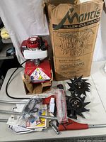 Engine unit on red housing with fuel tank, two blades, handle parts and hardware laid out