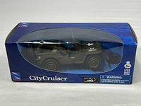 Side view of Newray 1:32 scale Jeep Willys diecast model in olive drab, packaged in blue City Cruiser box with window display.