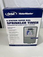 Front view of the sealed box showing the Orbit WaterMaster 4 Station Super Dial Sprinkler Timer with main features and model number 57974.