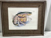 Framed print of a rainbow trout with fishing reel, featuring detailed colors and artistic design, inside a wooden frame.