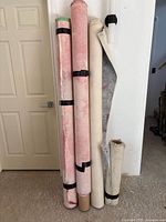 Four rolled canvases leaning against wall