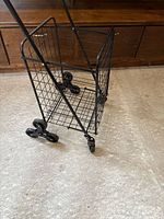 Side view of unfolded black metal utility cart showing wire basket and wheel arrangement