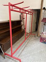 Full view of red metal clothing rack showing casters and frame