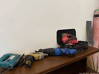 All four corded power tools on wooden shelf