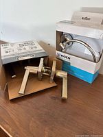 Open box showing Defiant lever handles and Moen towel ring box