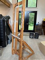 Front angled view of full wooden H-frame easel showing paint splatters and adjustable tray