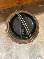 Top view of black metal ashtray insert with swing-bar lid