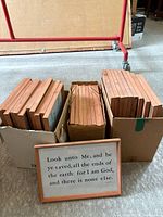 Three boxes containing stacks of reddish wood picture frames, one frame displayed in front