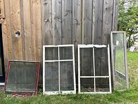Four window sashes leaning against wooden wall