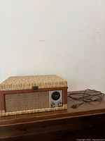 Record player closed showing front speaker grille and power cord