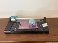 Top view of Staples rotary paper trimmer with installed turquoise blade carriage and sealed spare blade assembly