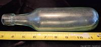 Side view of the bottle showing full length with tape measure for scale approximately 11 inches.
