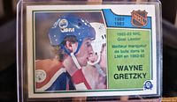Front of the 1983-84 OPC Wayne Gretzky hockey card showing the player in equipment with NHL and league achievement details.