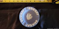 Top view of blue Wedgwood jasperware plate showing white classical figure and floral garlands as decoration