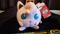 Single new Jigglypuff plush toy with tag visible, photographed against a black background with a measuring tape showing size.
