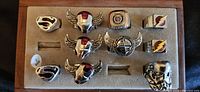 Photo showing all 10 rings arranged neatly in a wooden tray, depicting various superhero-themed logos and designs.
