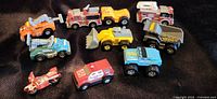 Top-down view of 10 Tonka Micro Metals die-cast toy vehicles arranged on floor surface in good condition.