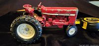 Side view of the vintage International Harvester toy tractor showing red paint, rubber tires, and wear.