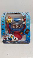 Front view of the M&M's chocolate candy dispenser in original packaging with colorful graphics and M&M's characters.