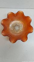 Top-down view showing the ruffled edge and sunburst pattern on the orange iridescent carnival glass bowl