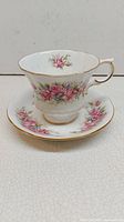 Side view of Paragon Flower Festival bone china teacup on matching saucer showing pink floral pattern and gold trim.