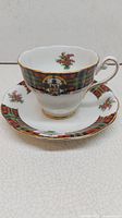 Fine bone china tea cup with Scottish tartan pattern, floral accents and gold trim handle and rim, placed on matching saucer