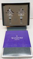 Two Waterford crystal star-shaped bottle stoppers in original box with branded sleeve.