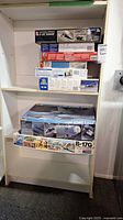 Shelf of assorted opened military aircraft kit boxes including F-15C Eagle and B-17G
