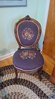 Front view of the wooden frame chair showing needlework floral upholstery on seat and backrest.