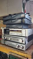 Stacked audio and video equipment showing Akai, Luxman, Realistic receivers and other components