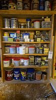Full view of wooden shelves holding multiple containers of screws, nails, and hardware items including tins and plastic tubs with labels.