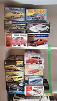 Photo showing a group of 13 model car kits in box form, featuring various classic cars including Corvette, Dodge Dart, Dodge Stealth, Viper, Mustang, Super Bee, and others. The boxes are opened.