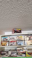 Photo showing 11 plastic model car kits arranged on shelves including Mustang Turbo Cobra, Corvette GS, 74 Camaro, and others
