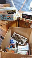 Cardboard box containing assorted plastic model kits including Tamiya M16 military vehicle and various automotive kits