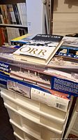 Photo showing multiple ship model kits stacked, including USS Olympia cruiser, with the Bobby Orr autobiography book on top.