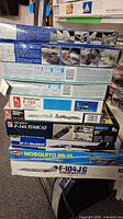 Stacked boxes of opened airplane plastic model kits showing various military aircraft, including F-15C, F-14A Tomcat, SR-71 Blackbird, Mosquito Mk VI, and F-104JG Starfighter.