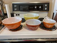 Four Pyrex mixing bowls arranged on stove showing size and color differences.