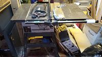 Front and right side view of Rockwell Beaver 10 table saw on metal stand with visible controls, hand wheels and rip fence.